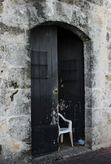 White plastic chair by the open black door. Entrance to apartment 44 from the street.
