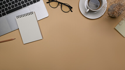 Comfortable workspace with laptop computer, glasses and notebook on beige background.