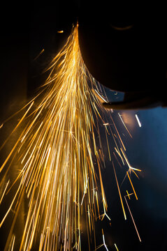 A glowing stream of sparks from a blade while cutting metal. Cutting disc for metal. Grinder. Work process. Work tool. Hand tool. Glowing sparks. Industrial equipment. Background image.