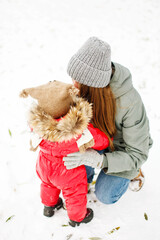 Unrecognizable young woman in winter casual outfit walking with her toddler kid