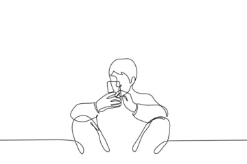 man sits leaning wall with back, apart and bent  knees holding phone with both hands - one line drawing vector