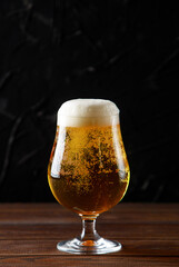 Glass beer with bubbles on wood background with copyspace