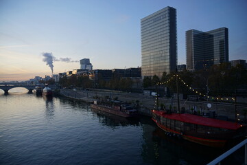 Obraz premium downtown skyline at sunrise with barges on seine river, old stone bridge and highway paris france