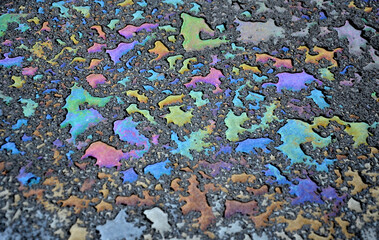 oil stain from leak in the car engine. oil after rain makes spots with rainbow reflections...