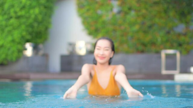 Happy Asian Woman in Swimsuit Playing and Spraying Water in Swimming Pool on Hot Summer Day, Slow Motion