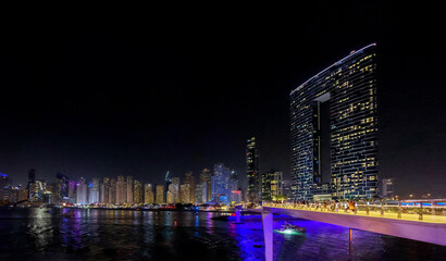 Panoramic view at night of Business Bay district with reflection in sea, UAE. Aerial sky at highest buildings in central Dubai, United Arab Emirates. High quality photo