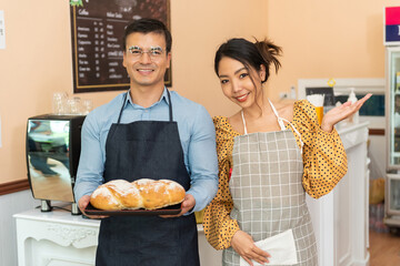 Cheerful business owners standing welcomingly together in front of the counter of their cafe.