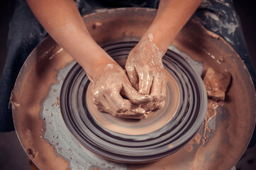 Hands of the master potter and vase of clay on the potter's wheel close-up. Master crock. Twisted potter's wheel.