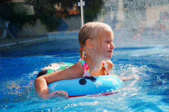 Alanya, Turkey - 09 30 2021: Blond preschool girl swimming in miсkey mouse rubber ring outdoors on summer sunny day 