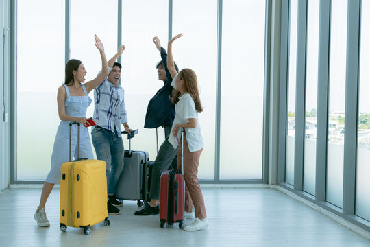 Asian young tourist friend group giving high-five during enjoy at airport terminal before journey.
