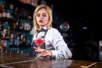 Girl barman creates a cocktail on the public house