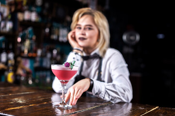 Girl bartender mixes a cocktail on the alehouse