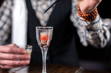 Young barman demonstrates his skills over the counter while standing near the bar counter in bar