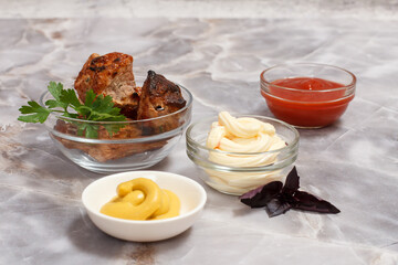 Grilled pork in a bowl with sauces and greens.