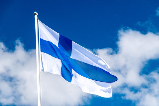 Finland national flag waving on blue sky. Flag of Finland also called Siniristilippu.