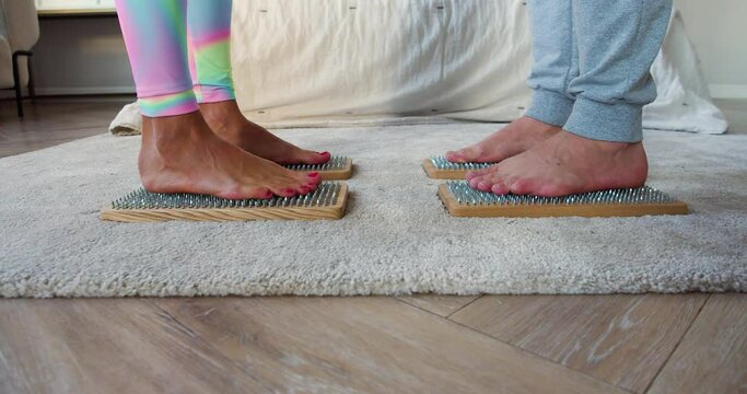 Mixed race couple stands on Sadhus boards with sharp nails opposite each other. Yoga practice.