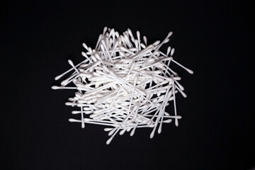 many white cotton swabs piled randomly on a black background