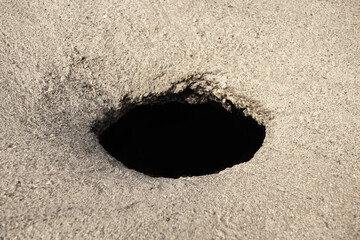 A hole in the asphalt pavement. Side view
