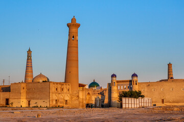 Fototapeta na wymiar View of city of Khiva (Uzbekistan) from side of station, first thing that traveler sees. Early morning sun illuminates streets that haven't yet woken up. Ancient minarets and domes are visible