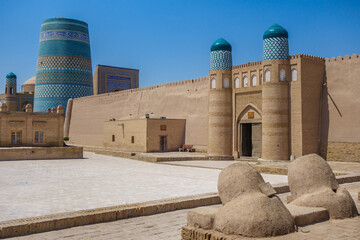 Central historical square in front of Khan palace Konya Ark, Khiva, Uzbekistan. Small building at gate is zindan (former prison). Famous Kalta Minor minaret is behind. Traditional furnaces on front