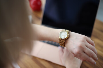 Office worker woman look at time on wristwatch and wait end of shift