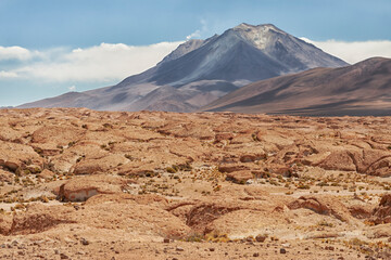 Bolivia, Atacama Desert. An active volcano rises above an old lava field.