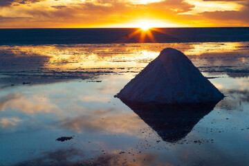 Bolivia, Uyuni, Salar de Uyuni. A salt cone sits in the water on the flats at sunset.