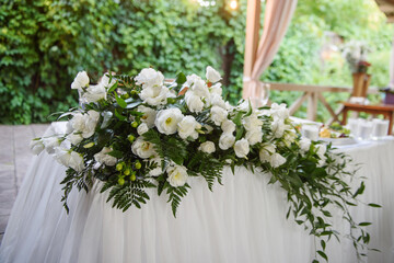 Beautiful floral arrangement of white flowers and greenery on wedding table in restaurant, copy space. Luxury wedding decorations. Table setting