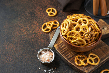 Mini pretzels with salt in a wooden bowl on a dark kitchen table