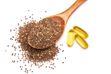 Wooden spoon full of organic natural chia seeds and and omega pills close-up