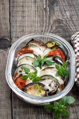 Baked vegetables with cheese and greek basil on wooden table