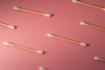 Pattern eco friendly bamboo ear sticks on a pink background. Eco friendly background with ear sticks. 