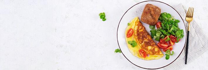 Omelette with tomatoes, ham, cheese and corn salad on plate.  Frittata - italian omelet. Top view, banner