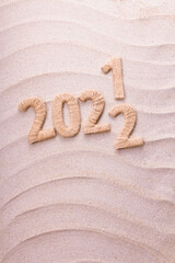 Year change concept. New 2022 succeeds 2021 on the beach in the sand