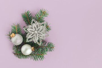 Spruce branches and christmas ornaments on a violet background. Christmas background.