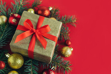 Fototapeta na wymiar Gift box with spruce branches, red and golden balls on a red background. Holiday concept.