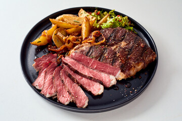 Tasty grilled steak and rustic potatoes on plate