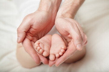 Obraz na płótnie Canvas Baby feet cupped into father hands