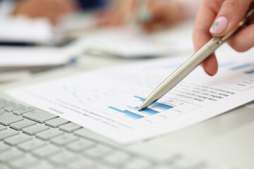 Man going through financial report paper with silver pen