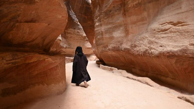 Stunning view of a person walking in The Siq. The Siq is the main entrance to the ancient Nabatean city of Petra in southern Jordan.