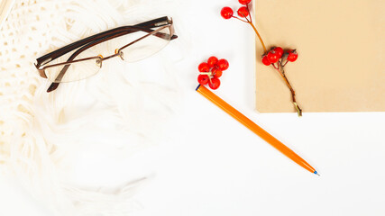 Autumn or winter composition. rowanberry, glasses, autumn leaves, beige sweater on a white background. Flat lounger, top view, copy space