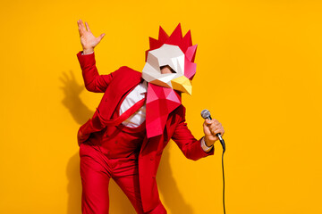 Photo of positive charismatic guy hold mic sing song wear rooster mask red suit isolated yellow color background © deagreez