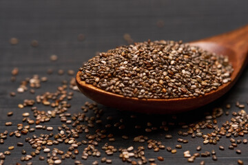 Bowl of organic natural chia seeds close-up on wooden background or table