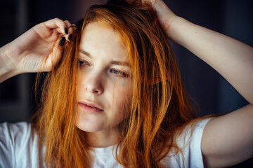 Fototapeta premium Portrait of sexy young woman touching long red hair. Female model posing in the studio, face close-up.