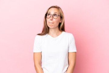 Young English woman isolated on pink background having doubts while looking up