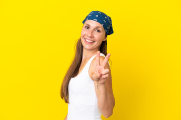 Young English woman isolated on yellow background smiling and showing victory sign