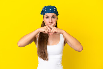 Young English woman isolated on yellow background showing a sign of silence gesture