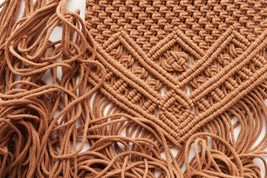 Handmade macrame pattern close up. Macrame braiding and cotton threads on wooden table.  Female hobby.  ECO friendly modern knitting DIY natural decoration 