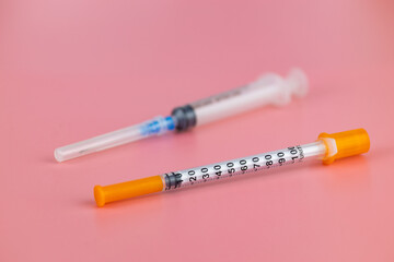 Insulin syringe and medical syringe pink background.