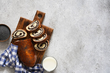 Pie with poppy seeds and milk. Roll on a wooden board top view.